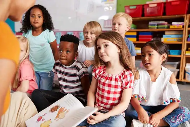 Children listening to a teacher read a book